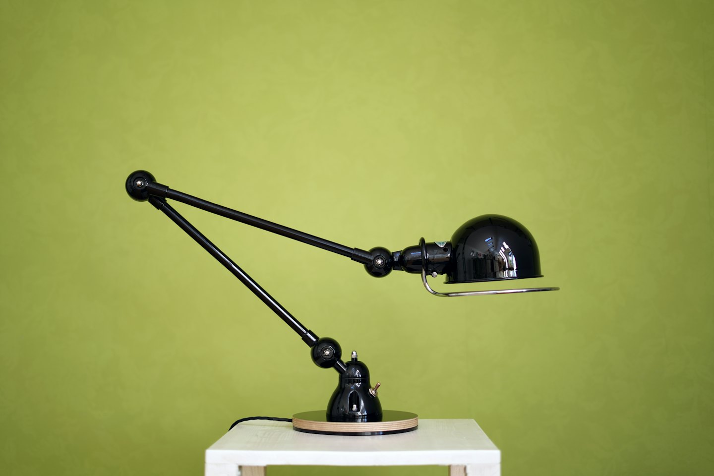 Una lampada da scrivania nera con base in legno su un tavolo.